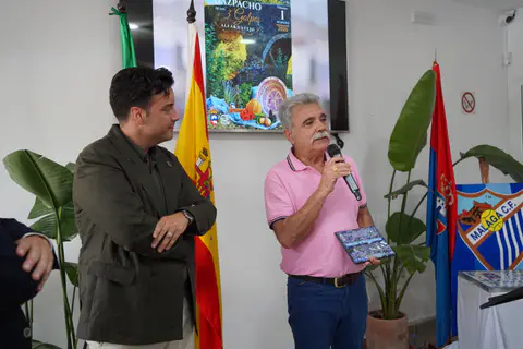 Un asistente habla con un micrófono junto a una bandera de España y elementos blanquiazules.