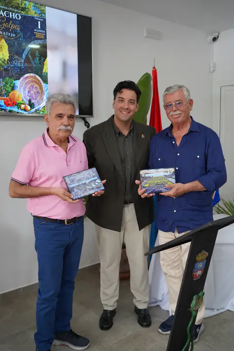 Tres asistentes posan de cuerpo entero con dos placas conmemorativas en el espacio del acto.