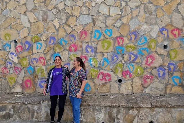 Dos personas ante un mural participativo formado por piezas de colores.