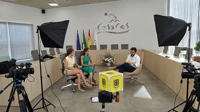 Set de entrevista con cámaras, luces y dos personas sentadas.