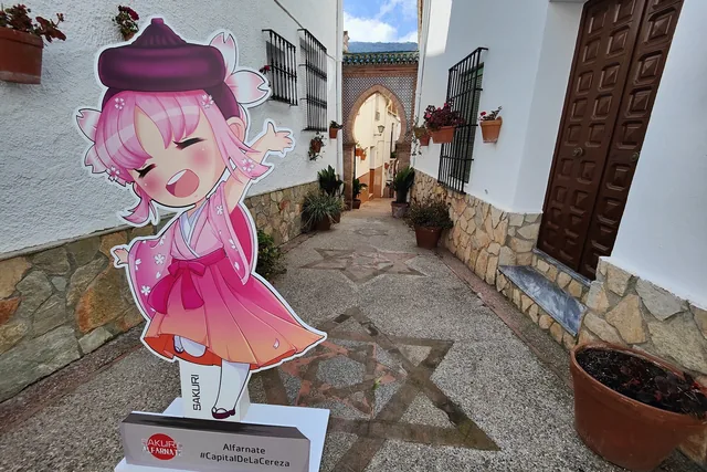 Figura ilustrada de Sakuri instalada en una calle blanca con macetas.
