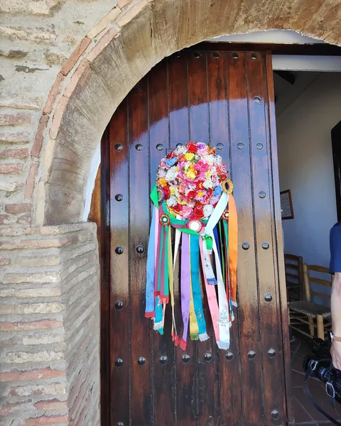 Adorno de cintas multicolores colgado en una puerta de madera.