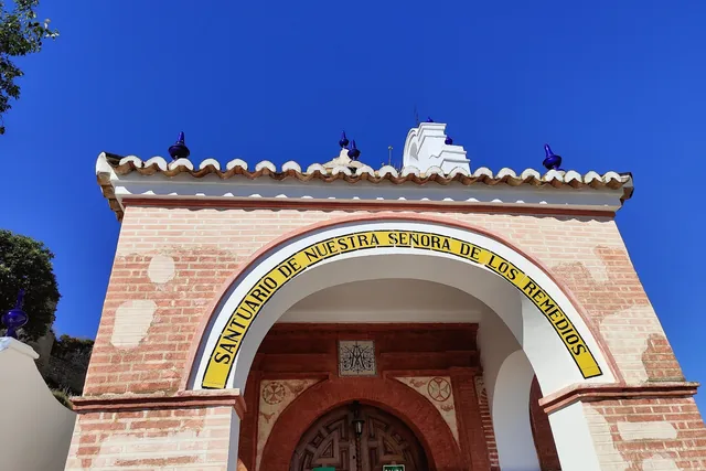 Fachada de una ermita bajo un cielo azul intenso.