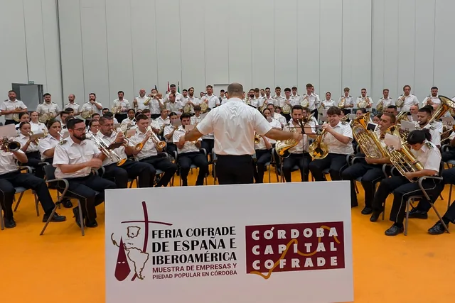 Orquesta interpretando música ante un rótulo de Córdoba Capital Cofrade.