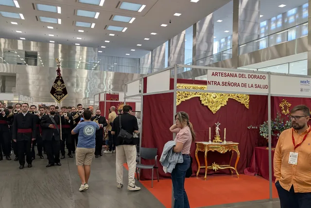 Pasillo de feria con expositores y visitantes.