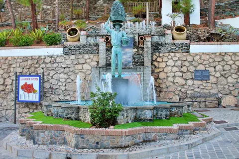 Fuente escultórica ante un muro de piedra en El Borge.
