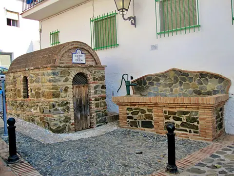 Fuente y construcción tradicional de piedra en una calle de El Borge.