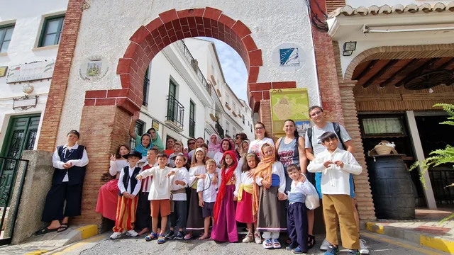 Grupo reunido bajo un arco de ladrillo rojo y blanco.
