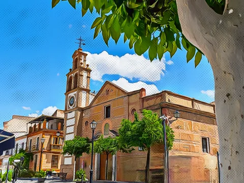 Iglesia de Cuevas Bajas vista desde una plaza arbolada.