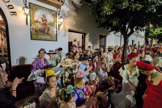 Pasacalles nocturno con trajes y adornos florales.