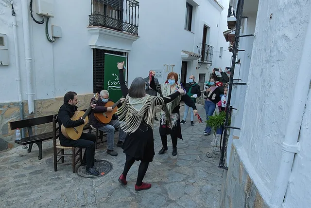 Músicos actuando en una calle blanca y estrecha.