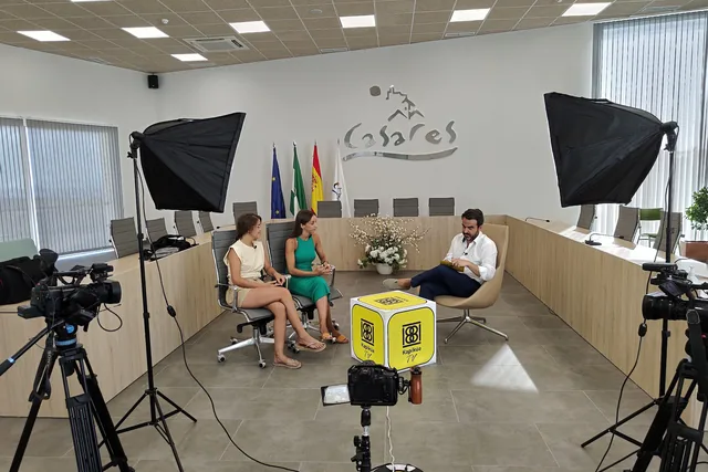 Set de entrevista con cámaras, luces y dos personas sentadas.