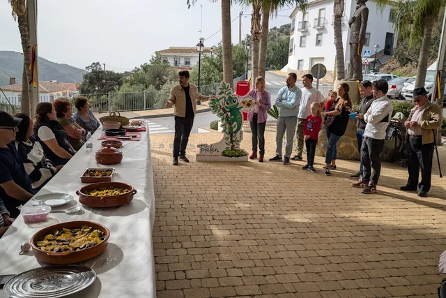 Mesa larga con platos preparados en una calle.