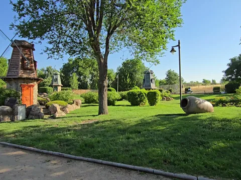 Parque arbolado con esculturas y césped.