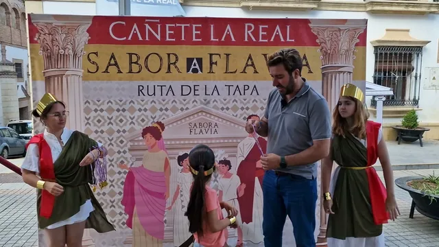 Personas ante un fondo gráfico de SaborA Flavia en una plaza.