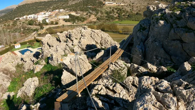Pasarela de madera suspendida sobre un paisaje rocoso de montaña.