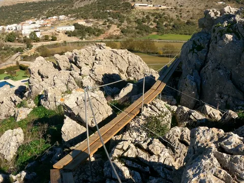 Pasarela de madera suspendida sobre un paisaje rocoso de montaña.