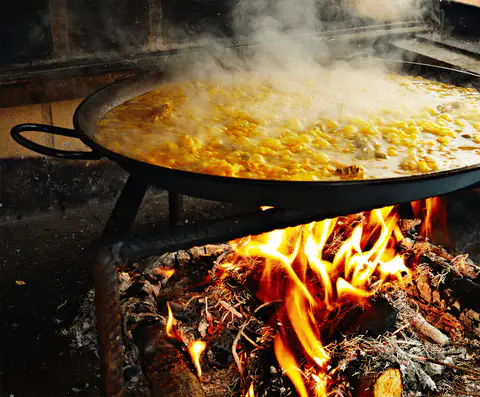 Paella cocinándose a fuego de leña.